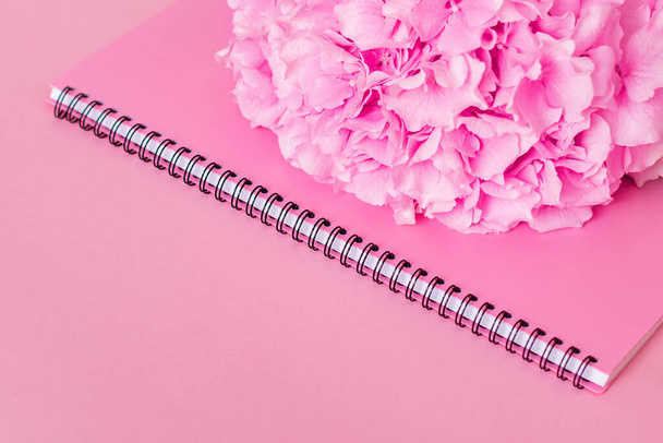 Notebook and hydrangea with copy space on pink background. Stylish background for beauty, fashion and business sphere - Photo, image