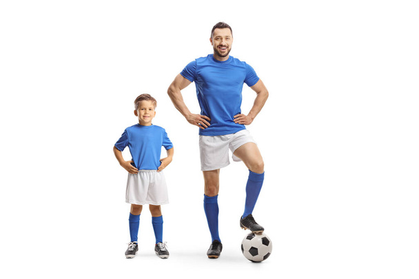 Young man and a boy with a soccer ball wearing blue sport jersey isolated on white background - Zdjęcie, obraz