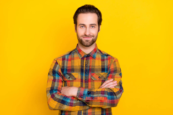 Photo of charming confident young guy dressed checkered shirt arms crossed smiling isolated yellow color background - Fotoğraf, Görsel