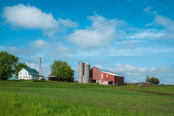 A farmstead with barns silos and a farmhouse up on a hillside of the rural backroads of Wisconsin - Photo, Image