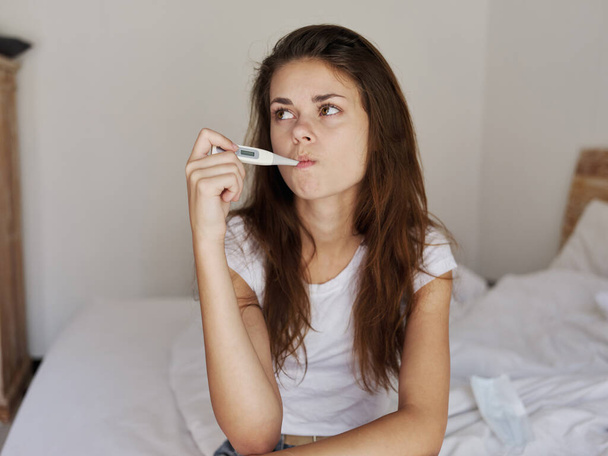 mujer con un termómetro en la boca esperando el resultado de la temperatura - Foto, Imagen