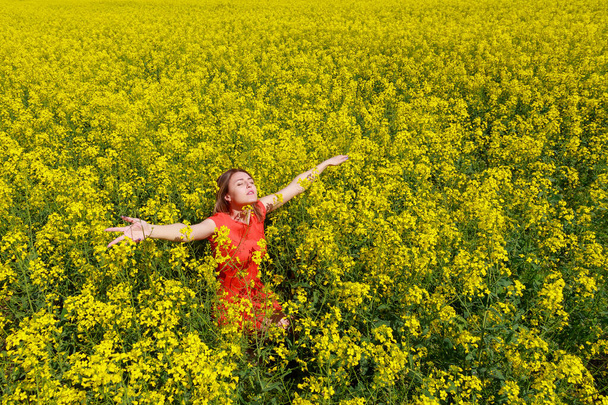 Молода красива жінка в кольоровій сукні на блискавці веселий жовтий фон квітучого ріпакового поля. концепція свободи
 - Фото, зображення