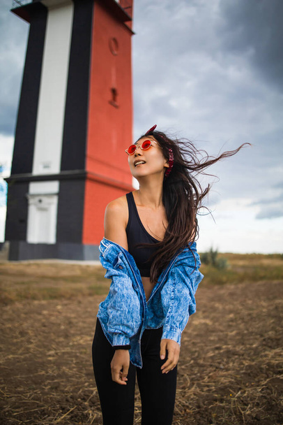 Mujer asiática turismo faro paisaje marino en Europa viajes recreación al aire libre concepto de estilo de vida. chica pelo en el viento usando una chaqueta de mezclilla - Foto, imagen