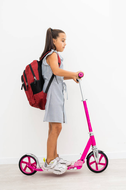 little schoolgirl on a scooter on a white background - Foto, Imagem