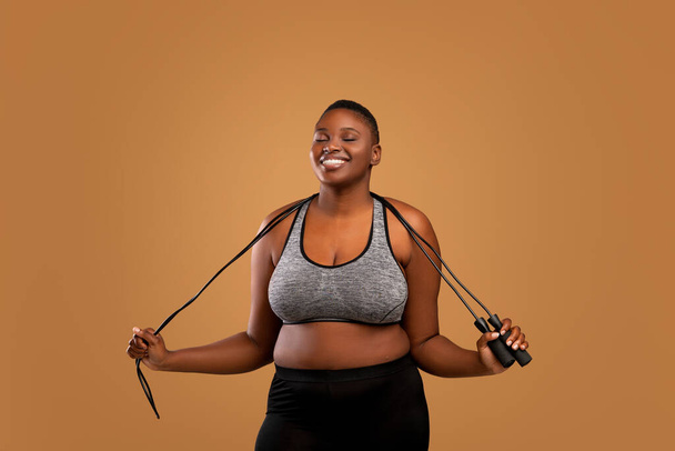 czarny pulchny kobieta pozowanie z skakanie liny w studio - Zdjęcie, obraz