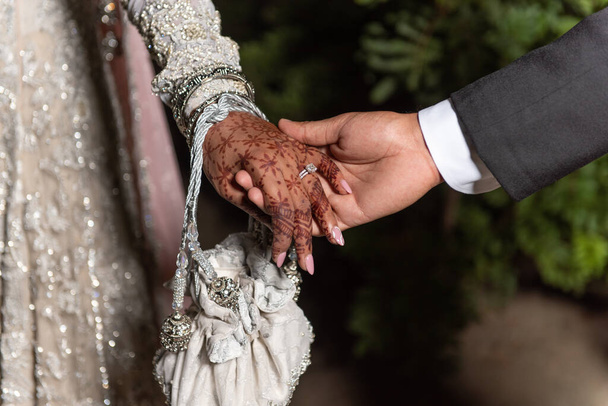 Madndi Henna dövmesi gelinin ellerini kaplıyor. Damat düğün gününde elini tutuyor.. - Fotoğraf, Görsel