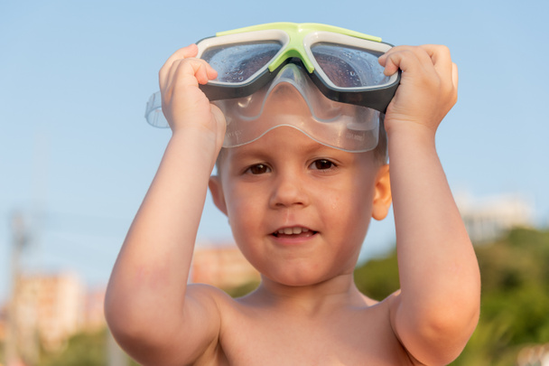 Güneşli bir sahilde dalgıç maskeli mutlu bir çocuğun yakın plan portresi. Dalış maskesiyle denizde bir çocuk - Fotoğraf, Görsel