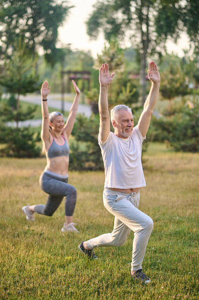 Two sportive mature adults exercising in the park - Fotoğraf, Görsel