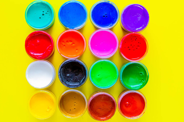 Many bright cans of paint stand together on a yellow background close-up. top view, flat lay, copy space, isolate. - Foto, imagen