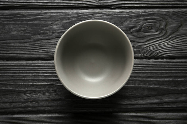 Stylish empty ceramic bowl on black wooden table, top view. Cooking utensil - Foto, Imagem