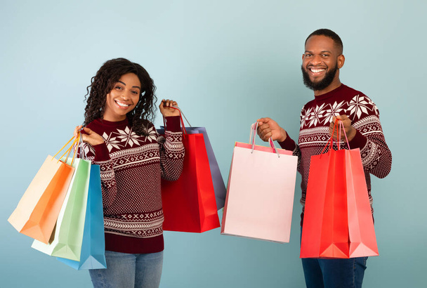 Viele Einkäufe, saisonales Verkaufskonzept. Glückliche afrikanisch-amerikanische Eheleute mit vielen bunten Einkaufstüten - Foto, Bild