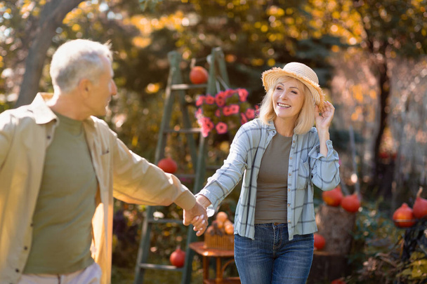Romantický starší pár držící se za ruce a procházející se v parku za teplého podzimního dne, šťastně v důchodu, volný prostor - Fotografie, Obrázek