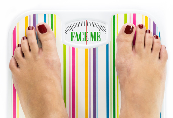 Feet on bathroom scale with words "Face me" on dial - Photo, Image