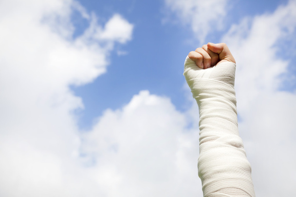 bandagierter Arm mit blauem Himmelhintergrund heben - Foto, Bild
