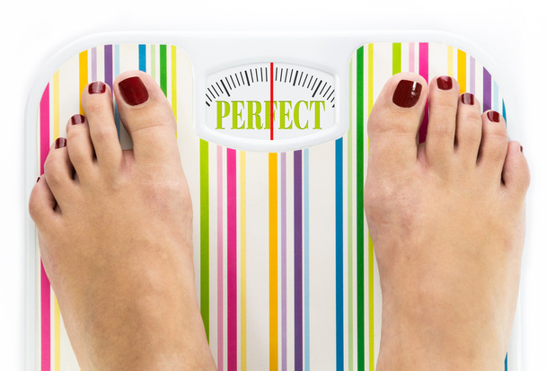 Füße auf Badezimmerwaage mit dem Wort "perfekt" auf dem Zifferblatt - Foto, Bild