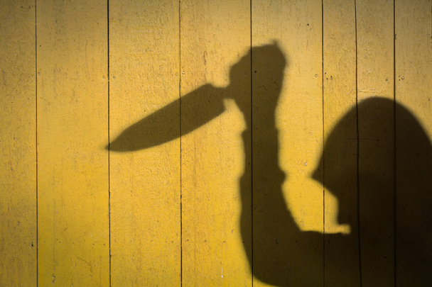 Мужская рука тени с кухонным ножом, на деревянной стене
 - Фото, изображение