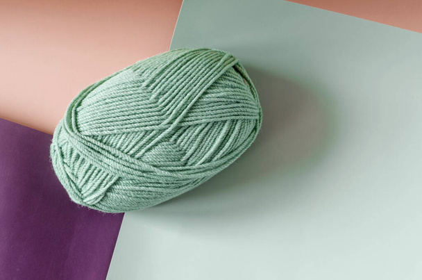 A ball of green yarn on a colored background close-up. Concept item for knitting and needlework on a colored background - Zdjęcie, obraz