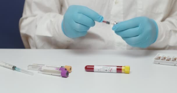 Primo piano delle mani del medico che indossano guanti blu utilizzando una siringa durante il test di laboratorio del vaccino coronavirus - Filmati, video