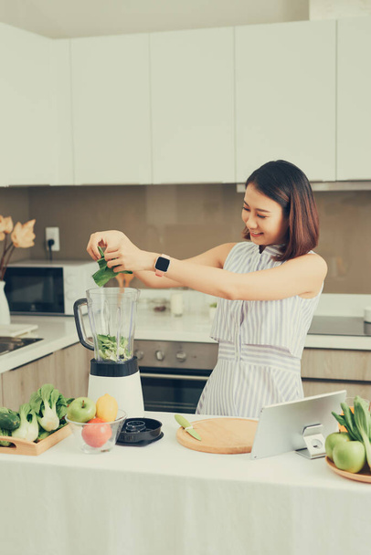 Zdravá asijská žena si vychutnat výrobu zelené zeleniny detox čistí a zelené ovoce smoothie s mixérem v kuchyni doma. koncepce stravování.zdravý životní styl - Fotografie, Obrázek