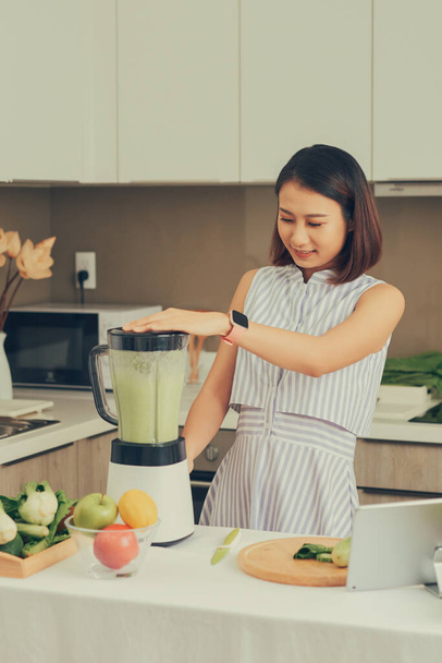 mooie jong aziatisch vrouw het maken van smoothie in blender in de keuken - Foto, afbeelding