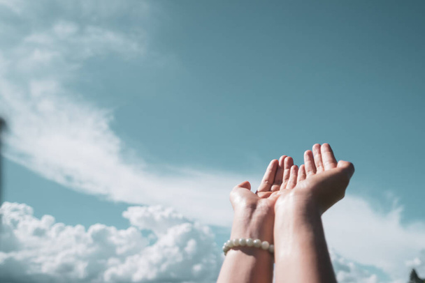 Γυναίκα χέρια θέση μαζί, όπως προσεύχεται μπροστά από τη φύση μπλε ουρανό φόντο. - Φωτογραφία, εικόνα