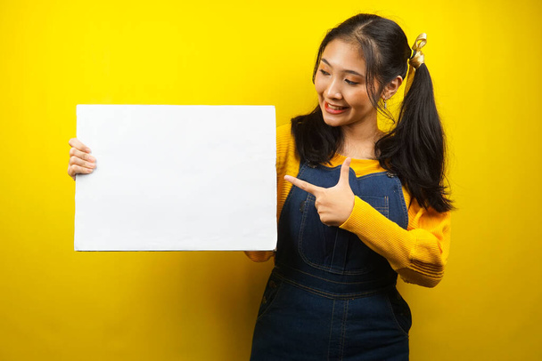 Pretty and cute young woman cheerful holding blank empty banner, placard, white board, blank sign board, white advertisement board, presenting something in copy space, promotion - Photo, Image