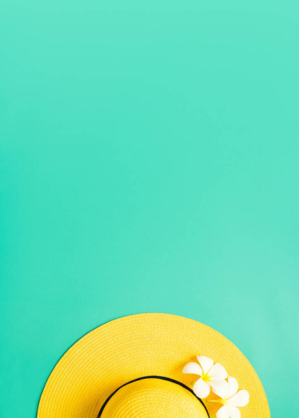 Yellow straw hat over green turquoise with white plumeria flower background with sunlight ,Minimal summer beach sea,vertical  - 写真・画像