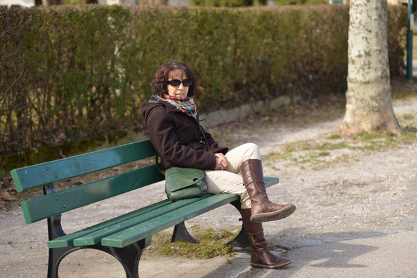 a beautiful mature woman sitting on a brench - Zdjęcie, obraz