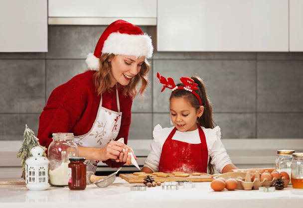 Mother and daughter making Christmas cookies in the kitchen  - Valokuva, kuva
