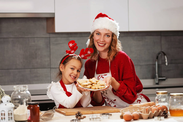 Mother and daughter making Christmas cookies in the kitchen  - Фото, изображение