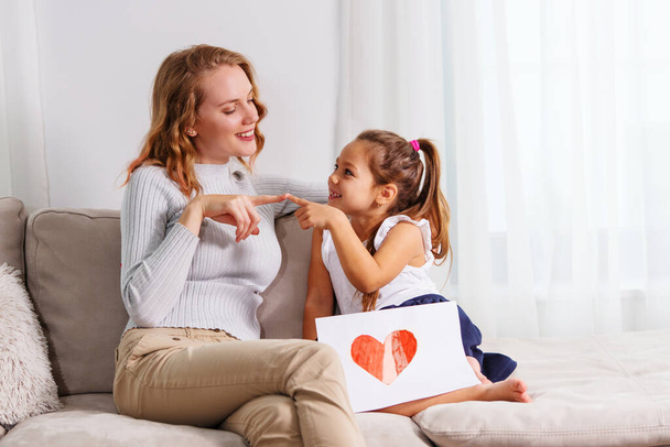Cute little girl giving a heart-drawing to her mother - Foto, Imagem
