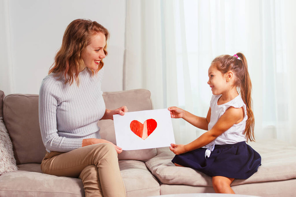 Cute little girl giving a heart-drawing to her mother - Foto, immagini