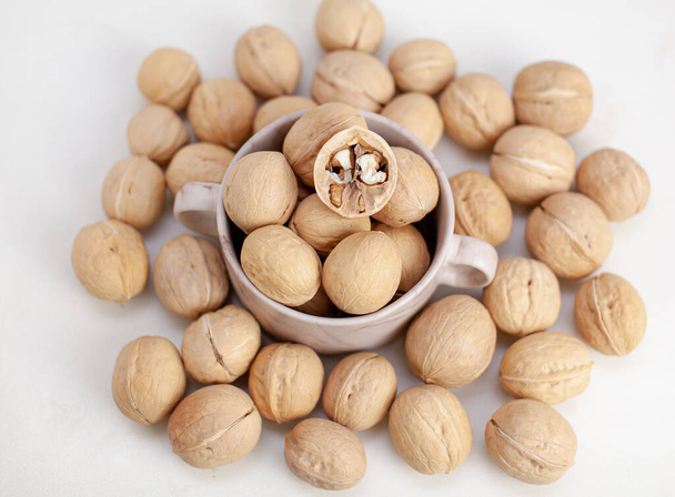 A lot of whole walnuts in a cup on a white background. Healthy food - Photo, Image