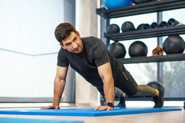 Young athletic man doing push-ups in a gym, close up - Photo, image