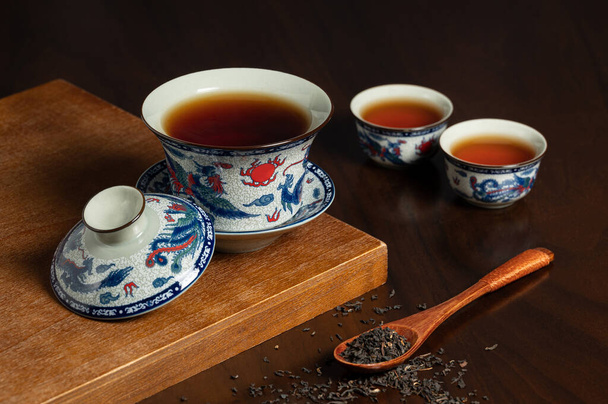 Traditionelle chinesische Porzellan Teetasse und Teeblatt auf hölzernem Anc - Foto, Bild