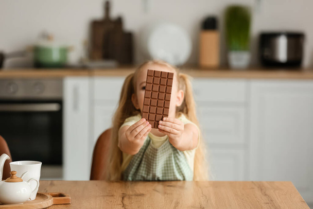 Χαριτωμένο κοριτσάκι με σοκολάτα στην κουζίνα - Φωτογραφία, εικόνα