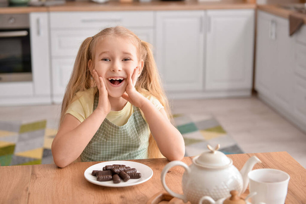 Cute little girl with chocolate in kitchen - Foto, afbeelding