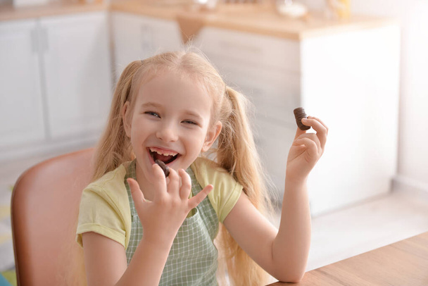 Aranyos kislány eszik édes csokoládét a konyhában - Fotó, kép