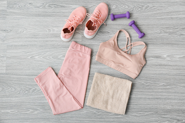 Sportswear, dumbbells, shoes and towel on light wooden background - Photo, Image