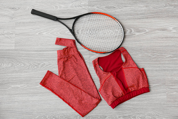 Sportswear and tennis racquet on light wooden background - Foto, afbeelding