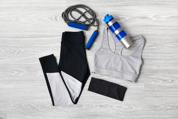 Vêtements de sport, corde à sauter et bouteille d'eau sur fond bois clair - Photo, image