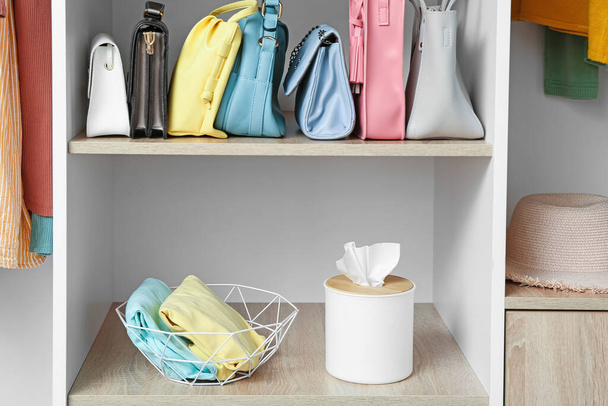 Moderno organizador con ropa y caja de pañuelos en estante en armario - Foto, Imagen