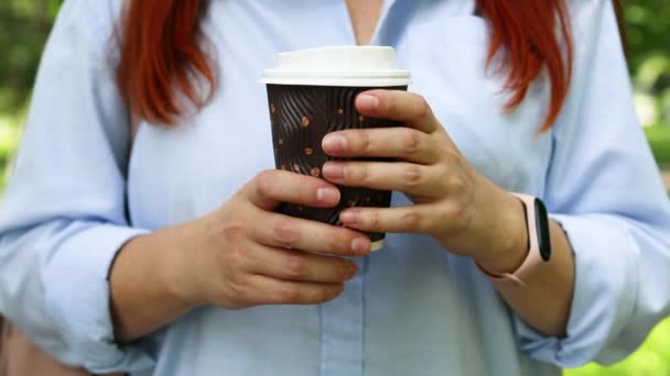 Naiskädet pitävät paperia kuppi kuumaa kahvia tai teetä juoda ulkona pilvisenä päivänä - Materiaali, video