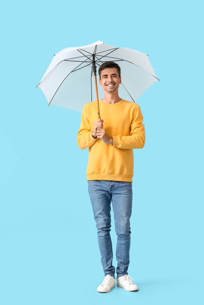 Stylish young man with umbrella on color background - Photo, Image