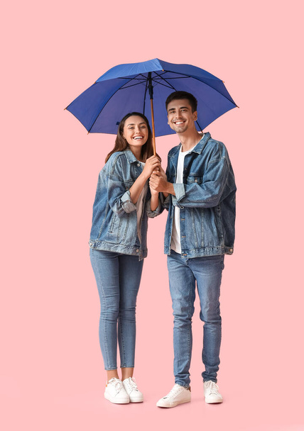 Young couple with umbrella on color background - Fotó, kép