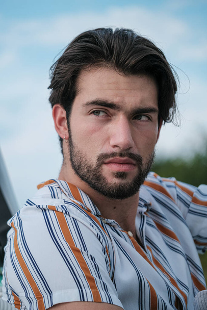 portrait of beautiful dark-haired italian model with light eyes and striped shirt with beard . High quality photo - Fotografie, Obrázek