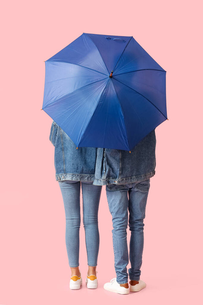 Young couple with umbrella on color background - Foto, afbeelding