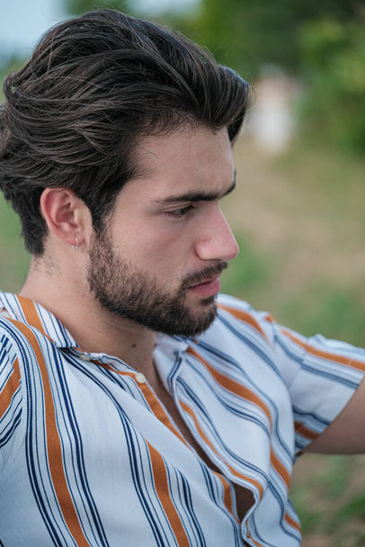 portrait of beautiful dark-haired italian model with light eyes and striped shirt with beard . High quality photo - Photo, Image