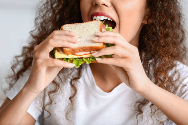 Genç Afro-Amerikalı kadın evde lezzetli sandviçler yiyor, yakından. - Fotoğraf, Görsel