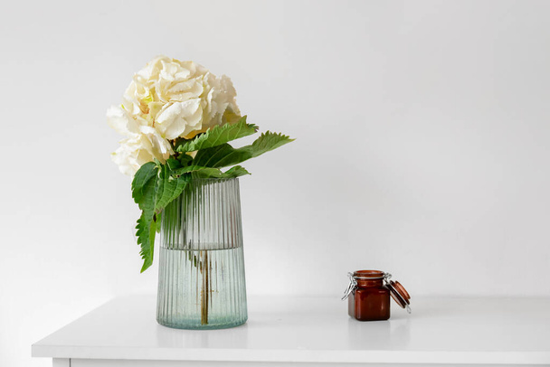 Váza s květinami hortenzie na polici u světelné stěny - Fotografie, Obrázek